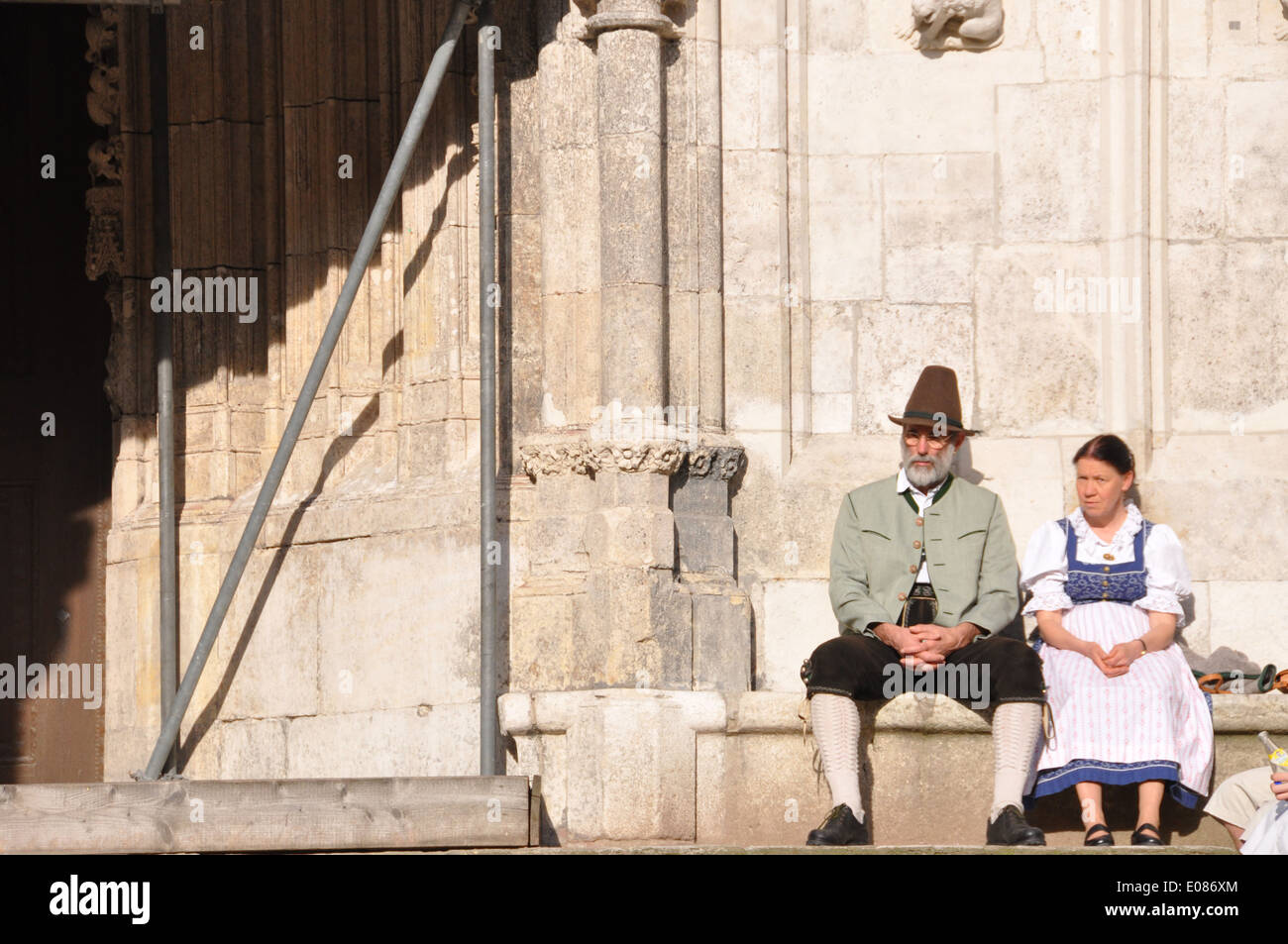 Un vieux couple allemand en costume traditionnel assis sur un banc à côté de l'entrée de la cathédrale de Regensburg. Banque D'Images