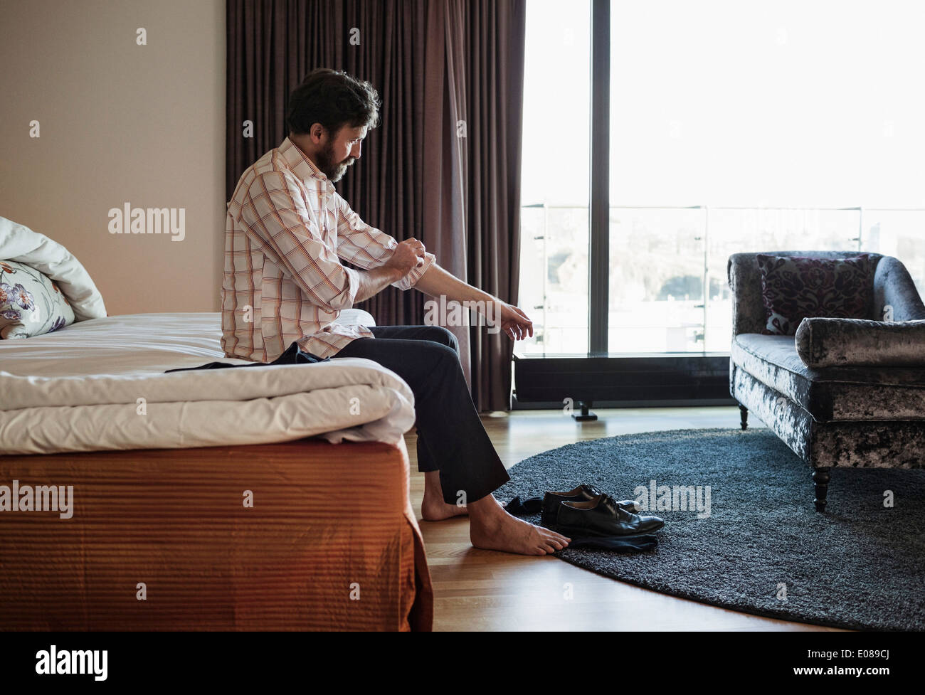 Businessman rolling dans sa manche dans la chambre d'hôtel Banque D'Images