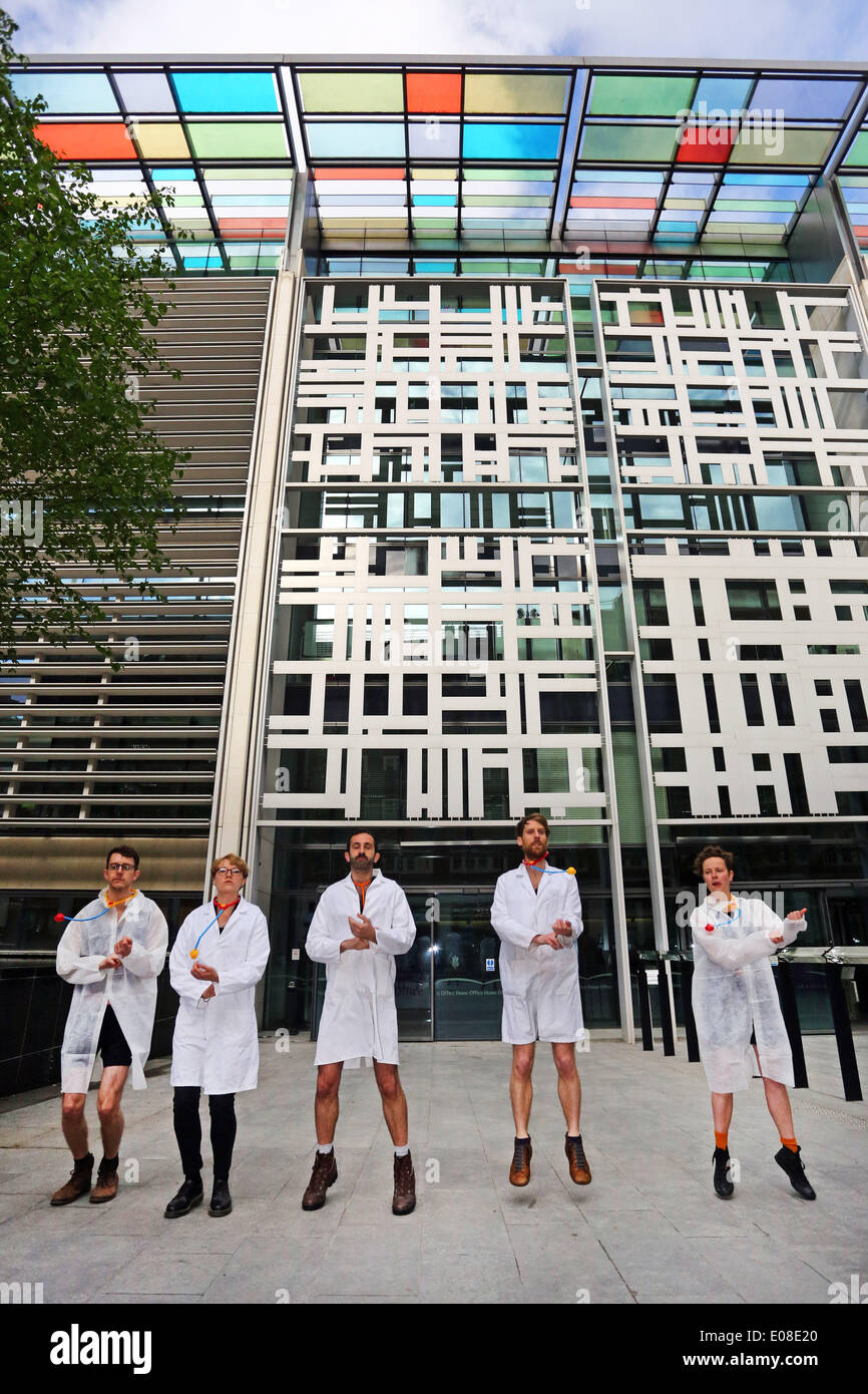 Londres, Royaume-Uni. 6e mai 2014. Act Up Docs flics pas de loi sur l'Immigration protester contre le Home Office à Londres avec les manifestants habillés en médecins stripping off de devenir policiers. ACT UP London se bat contre deux dispositions dans le projet de loi sur l'Immigration, qui servira à introduire des frais pour les services de santé, les médecins à leur tour, les agents frontaliers et d'augmenter l'infection par le VIH. Crédit : Paul Brown/Alamy Live News Banque D'Images