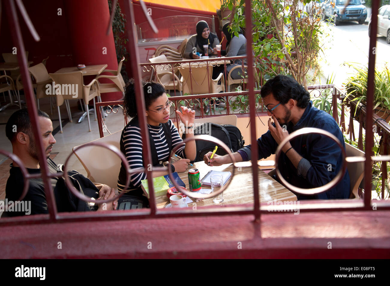 Tunis, Tunisie. Les jeunes dans un café à discuter et prendre des notes, dans l'arrière-plan deux jeunes femmes en tchador. Banque D'Images