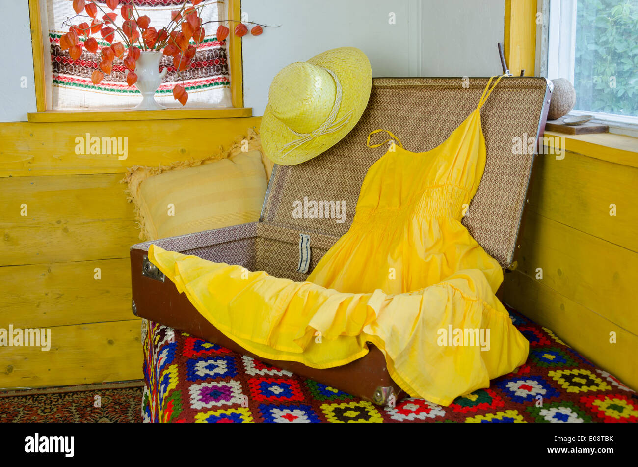 Ancienne valise ouverte sur le lit avec retro robe jaune paille et chapeau féminin Banque D'Images