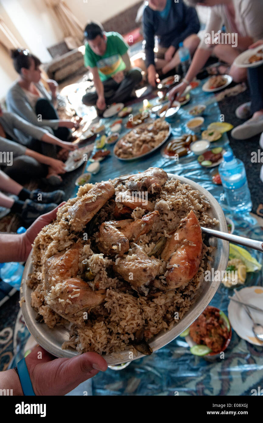 Un groupe de touristes ayant un déjeuner traditionnel avec une famille locale dans le village près de Orjan Al Ayoun trail. La Jordanie Banque D'Images