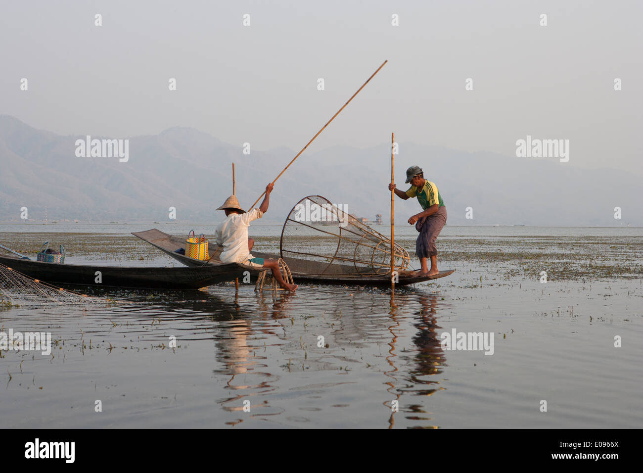 En Asie du sud-est de l'État Shan en Birmanie Myanmar Lac Inle jambe Nyaungshwe ethnie Intha aviron au crépuscule coucher de pêcheurs Les pêcheurs utilisent des moustiquaires Banque D'Images