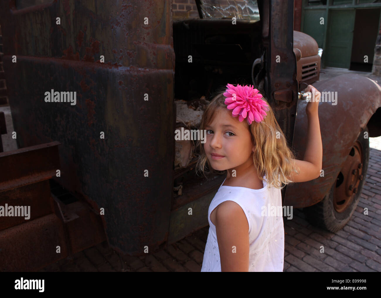 Portrait d'une jeune fille blonde dans une robe blanche avec une fleur rose pince à cheveux tenant une porte d'un vintage de camionnette, Toronto Banque D'Images