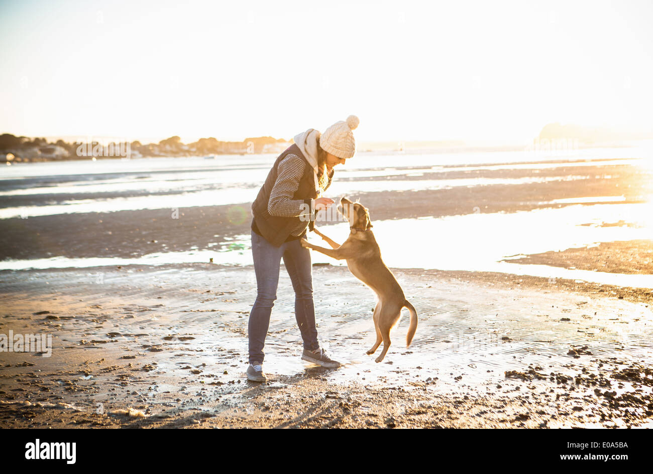 Jeune femme jouant avec son chien sur la plage Banque D'Images