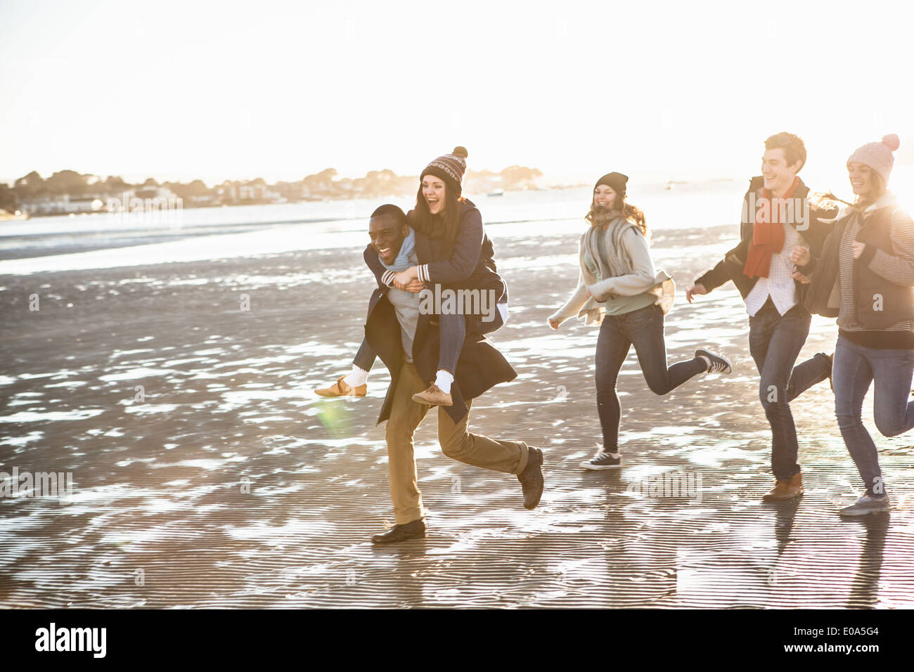 Cinq amis adultes fonctionnant sur la plage Banque D'Images
