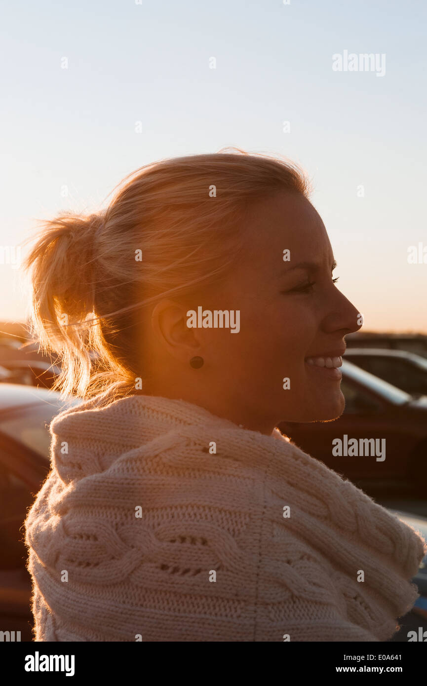 Smiling woman en stationnement au coucher du soleil Banque D'Images