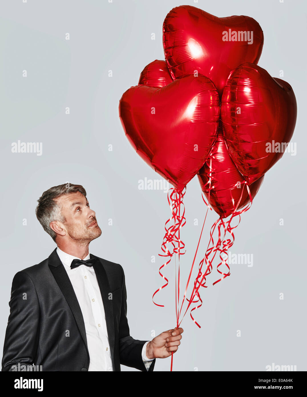 Portrait of man in tuxedo avec des ballons en forme de cœur Banque D'Images