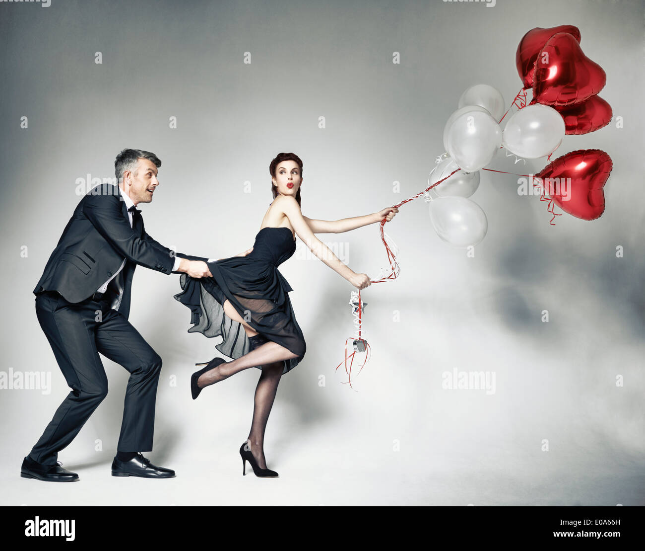 Tirant de l'homme robe femme avec des ballons en forme de cœur Banque D'Images