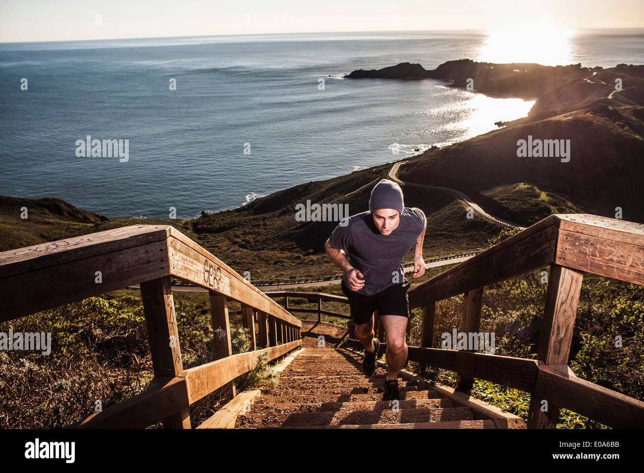 Jeune homme courir vers le haut escalier côtières au coucher du soleil Banque D'Images