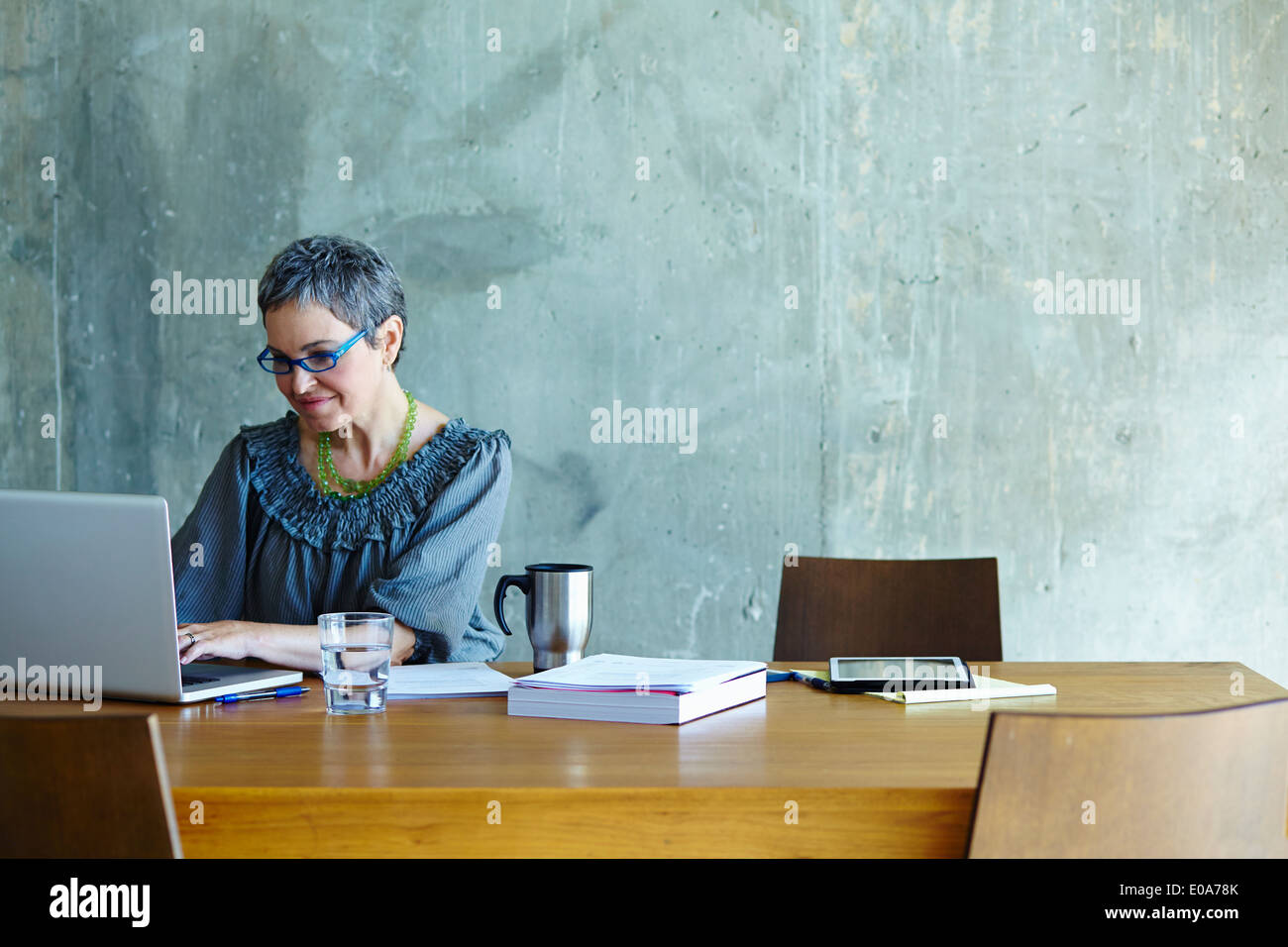 Femme mature at conference table working on laptop Banque D'Images