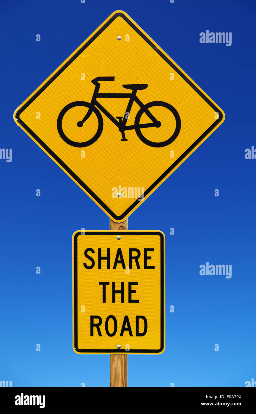 Partager la route avec les vélos panneau routier isolé avec fond de ciel bleu Banque D'Images