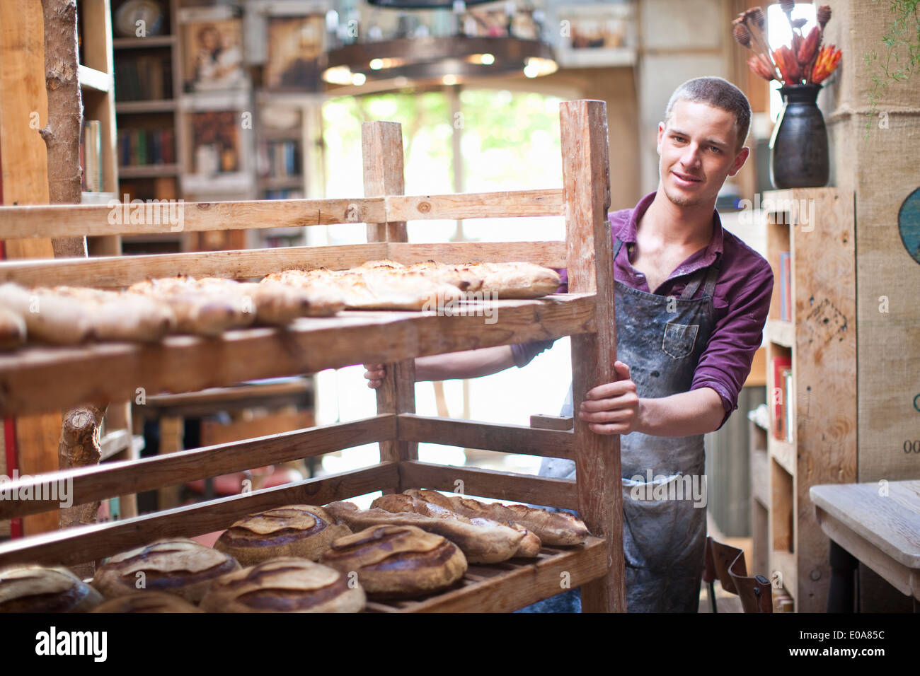 Portrait of young male baker avec étagères de pain frais Banque D'Images