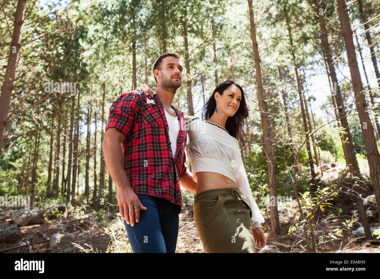 Jeune couple en train de marcher à travers la forêt, le bras autour de Banque D'Images