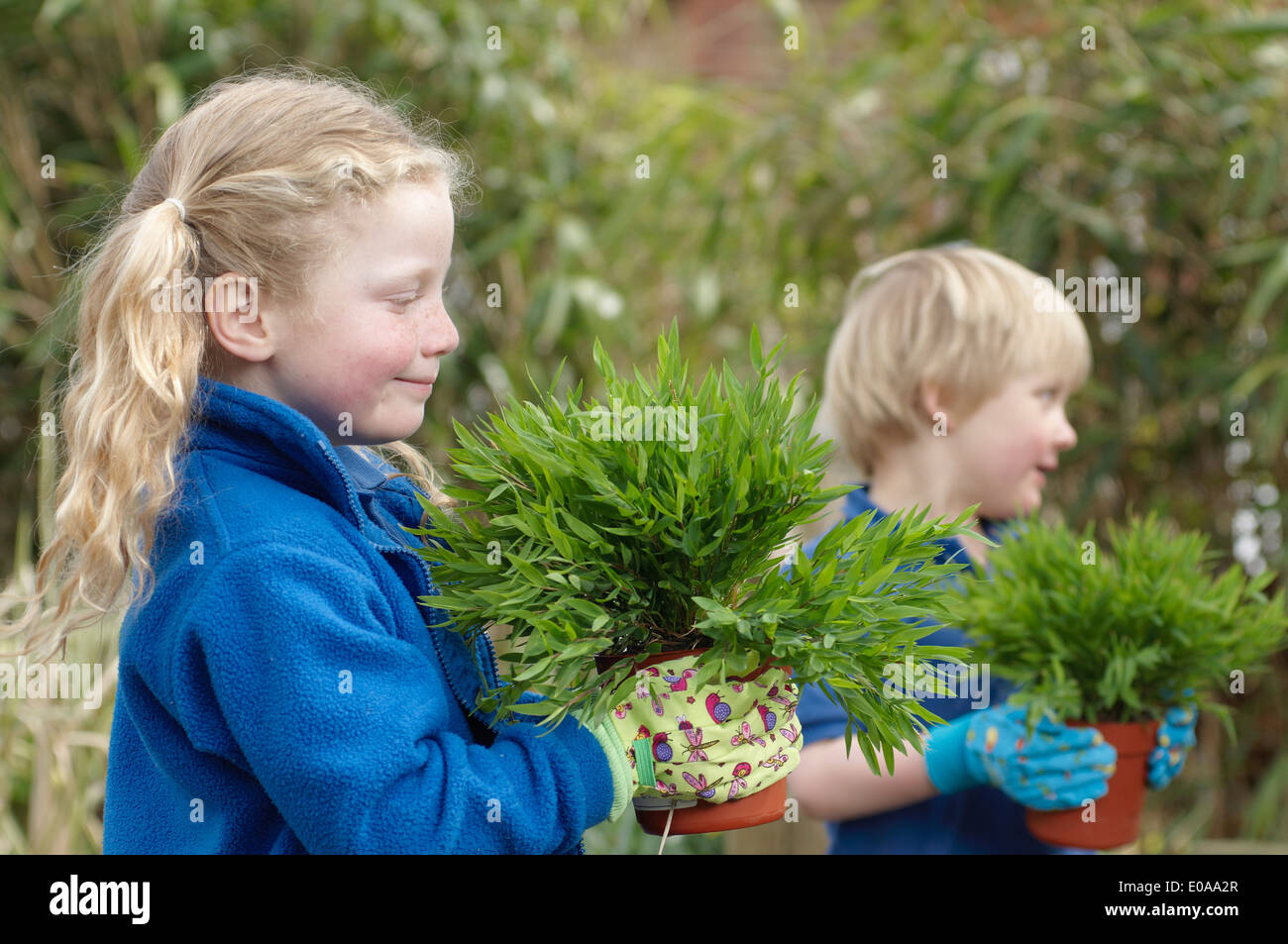 Garçon et fille de l'école avec des plantes dans le jardin Banque D'Images