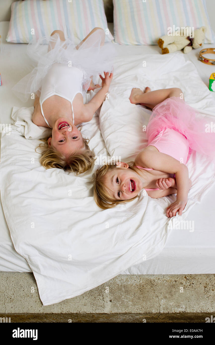 Portrait de deux jeunes sœurs jouer on bed Banque D'Images