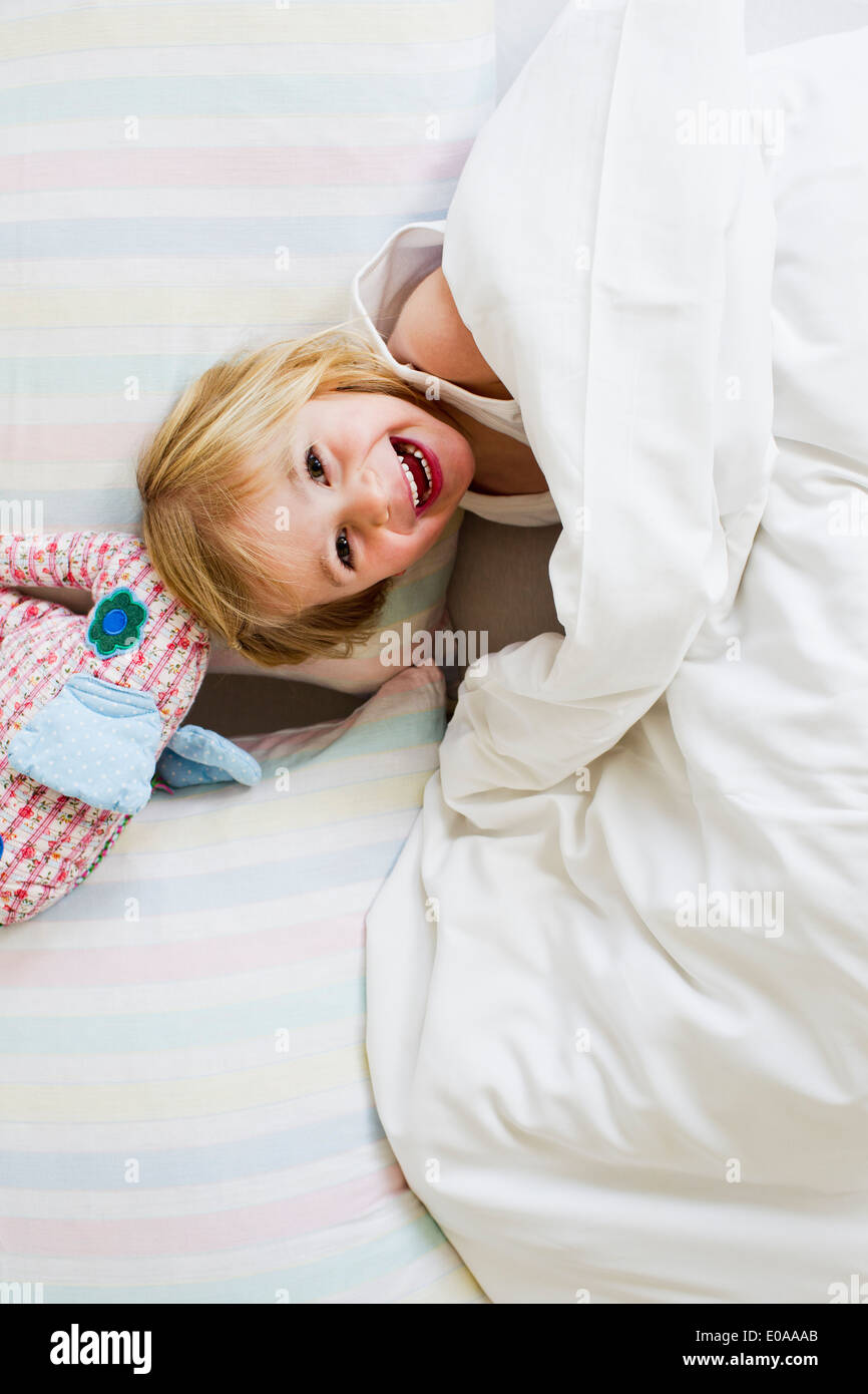 Portrait of young girl lying in bed with toy elephant Banque D'Images