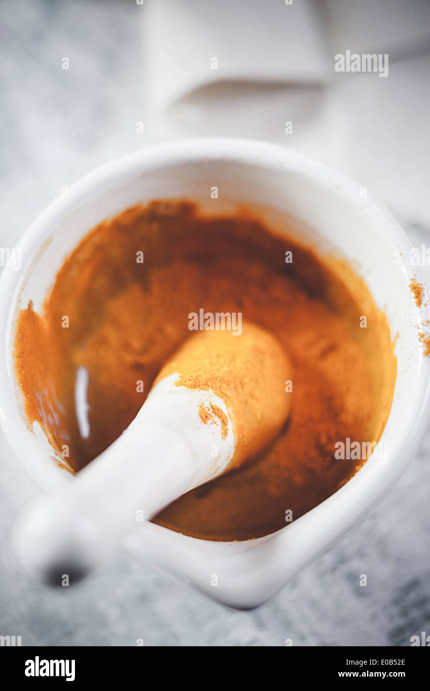 Poudre de curcuma mélangé à du miel dans le mortier pour thé au curcuma Banque D'Images