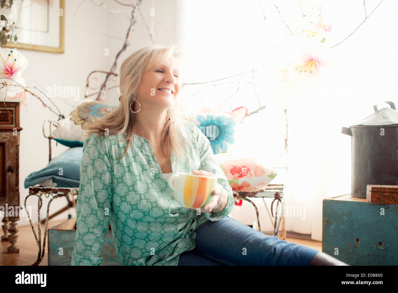 Mature Woman sitting on floor in living room Banque D'Images