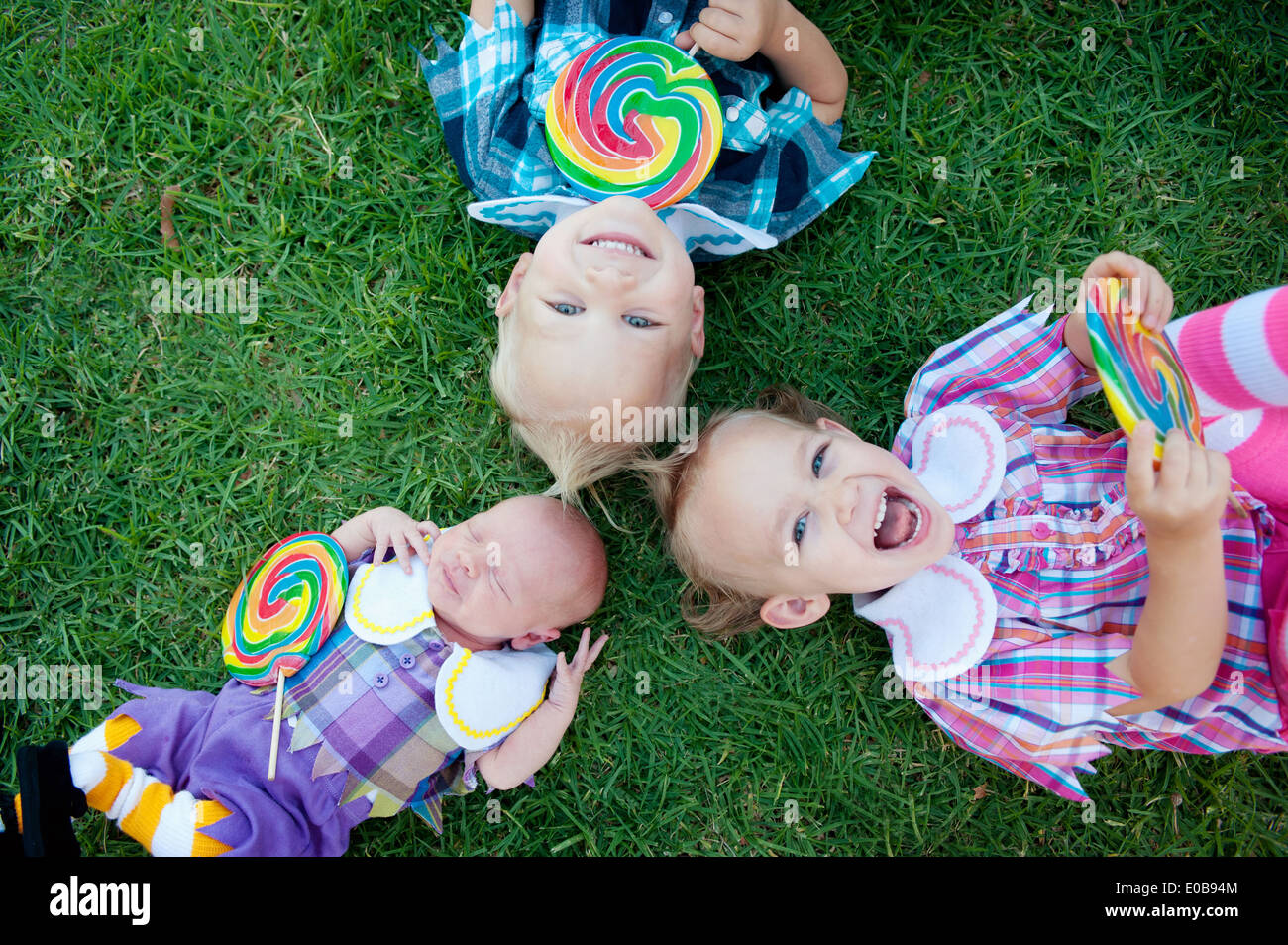 Frères et sœurs avec lollipops lying on grass Banque D'Images