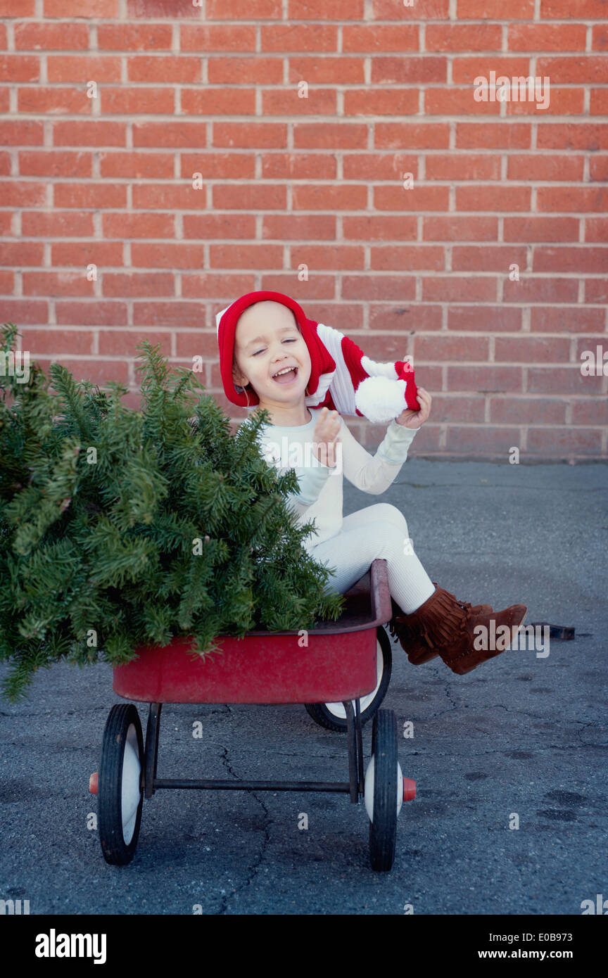 Fille assise dans une remorque avec arbre de Noël Banque D'Images