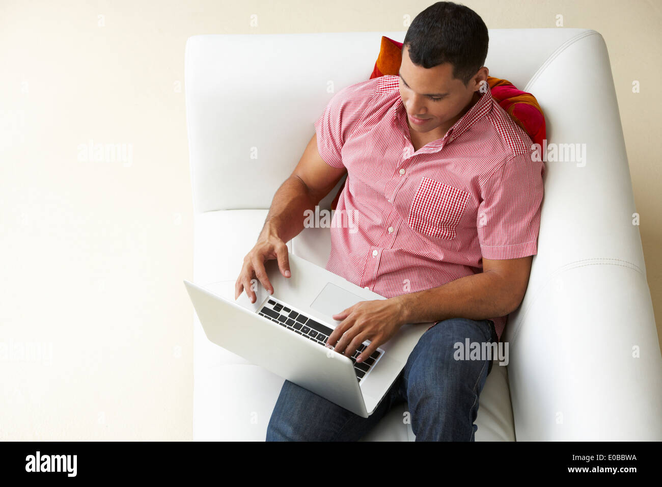 Vue aérienne de Man Relaxing On Sofa Using Laptop Banque D'Images Vue aérienne de Man Relaxing On Sofa Using Laptop Banque D'Images