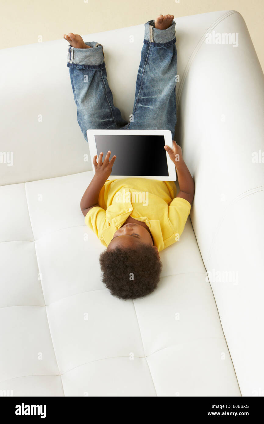 Vue de dessus de garçon sur le canapé à jouer avec Digital Tablet Banque D'Images Vue de dessus de garçon sur le canapé à jouer avec Digital Tablet Banque D'Images