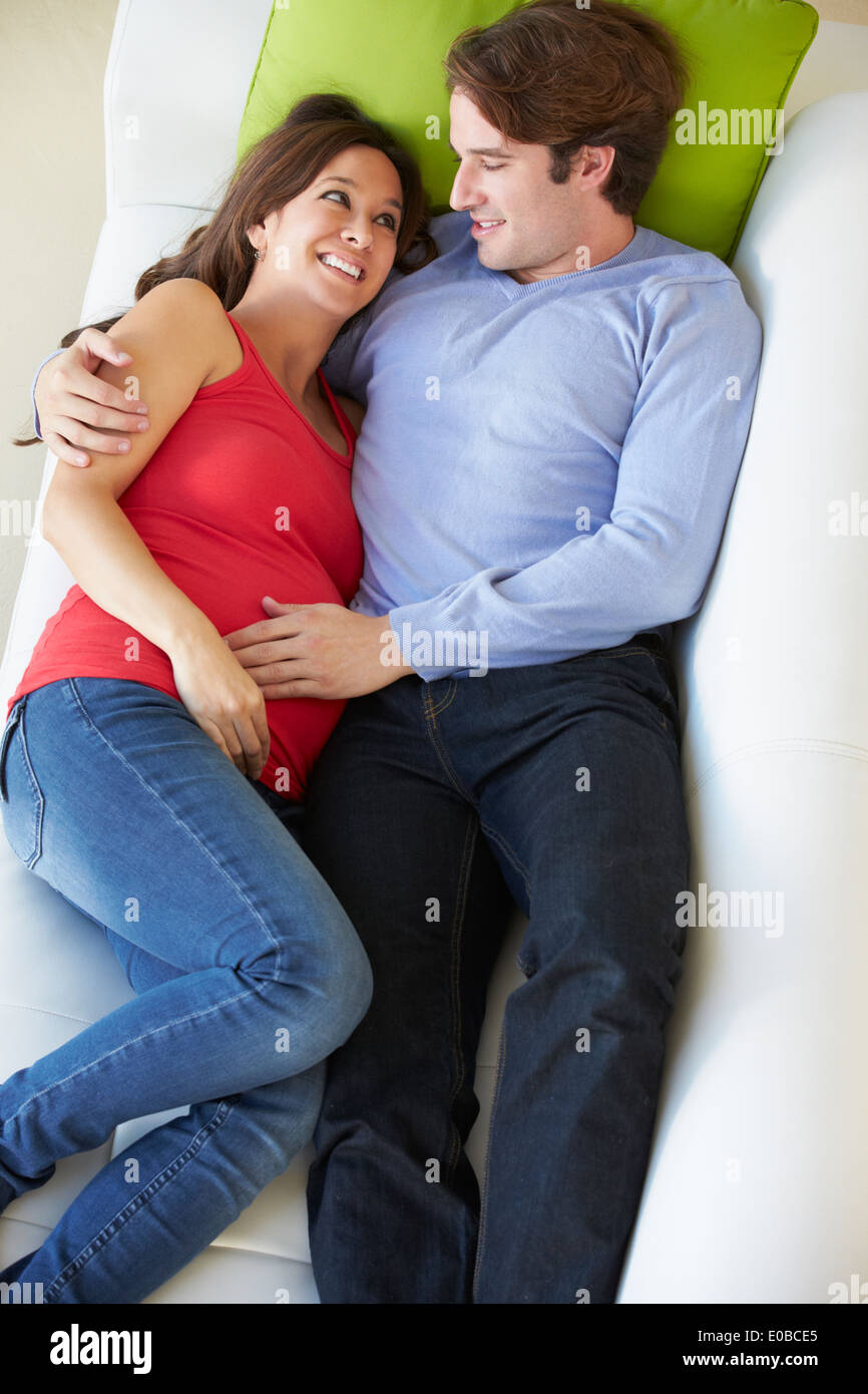 Vue aérienne de Man Relaxing On Sofa with Pregnant Wife Banque D'Images Vue aérienne de Man Relaxing On Sofa with Pregnant Wife Banque D'Images