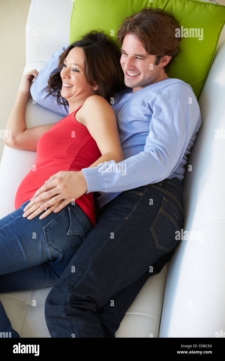 Vue aérienne de l'homme et de la femme enceinte en regardant la télé sur canapé Banque D'Images Vue aérienne de l'homme et de la femme enceinte en regardant la télé sur canapé Banque D'Images