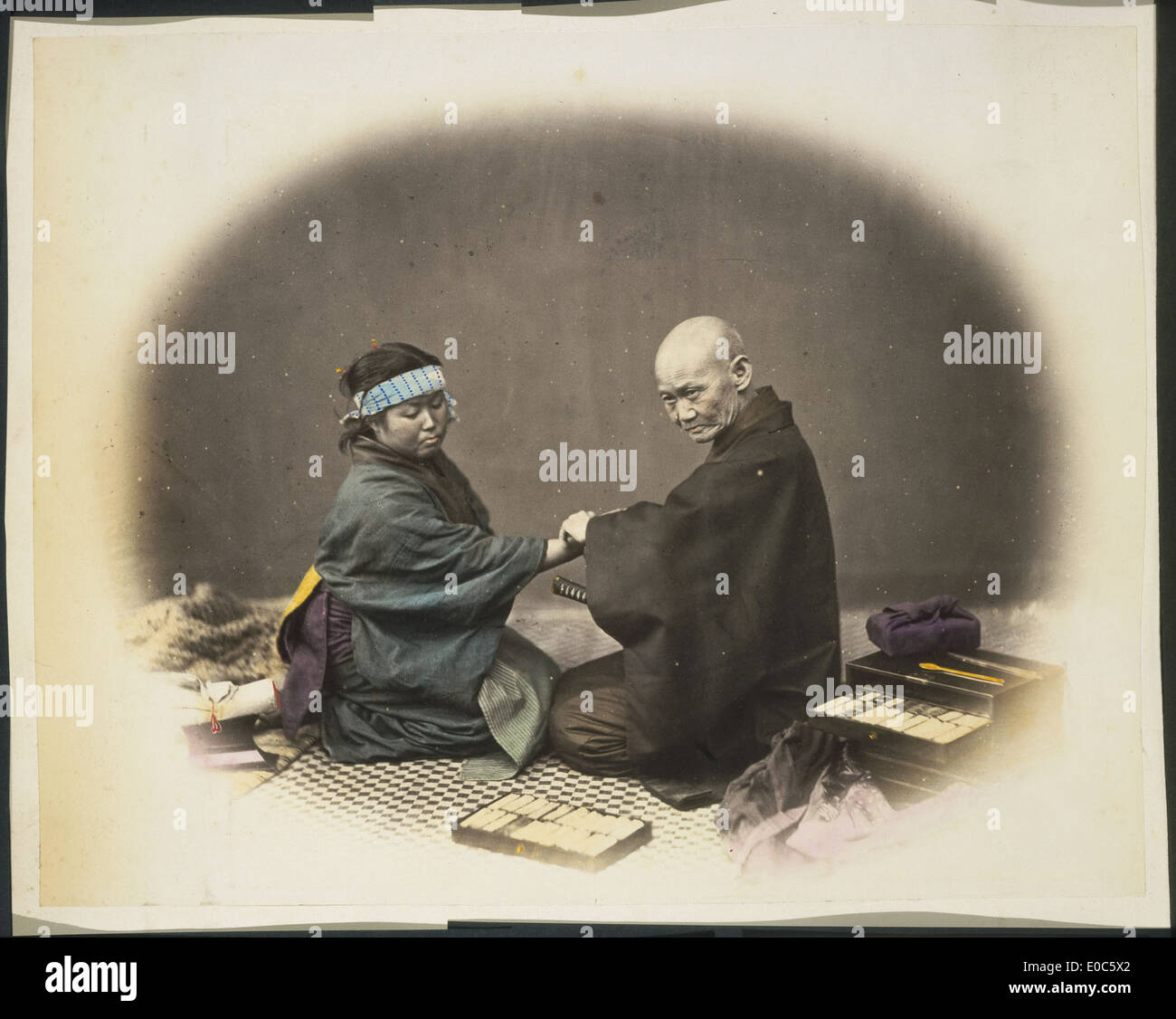 Cette image du Japon montre un médecin et un patient dans un contexte historique, offrant un aperçu des pratiques de soins de santé au cours de la période. La photographie met en évidence l'interaction entre un professionnel de la santé et une patiente. Banque D'Images