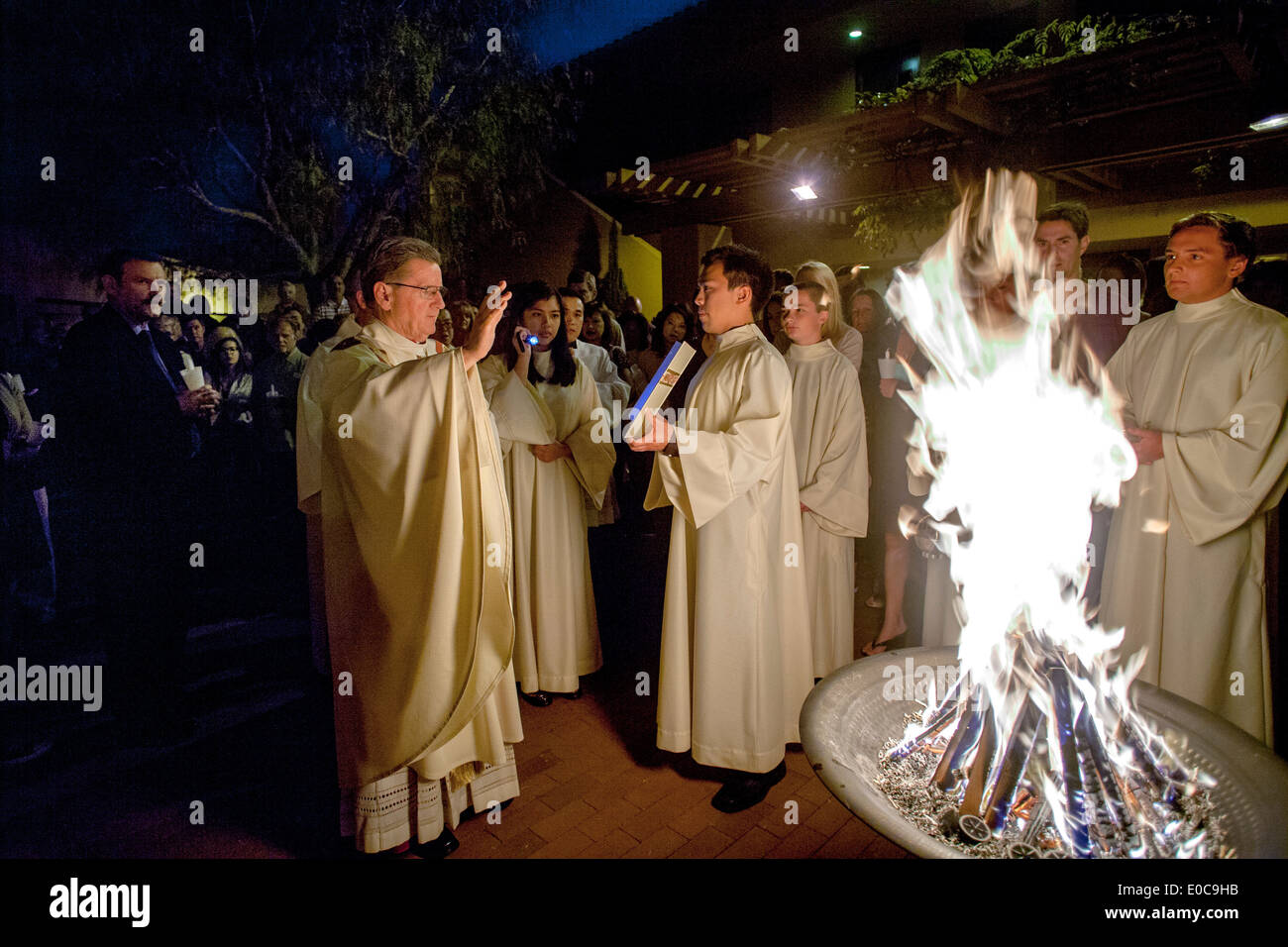 La robed pasteur de l'Église catholique saint Timothée, Laguna Niguel, CA, lit à partir de l'évangile à côté de l'incendie de Pâques au début de la grande nuit de Pâques. Banque D'Images