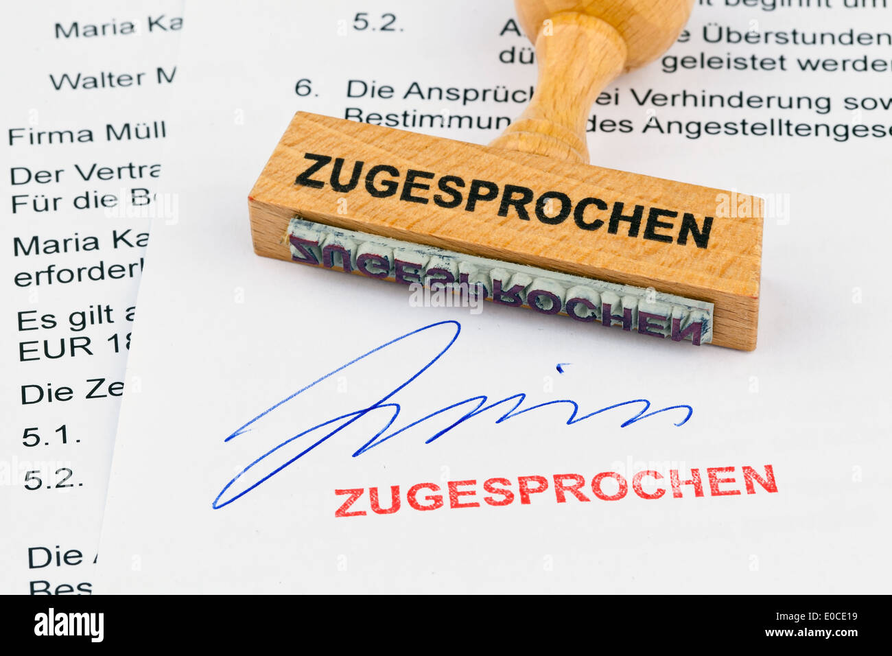 Un tampon de bois se trouve sur un document. Label décerné, Ein Stempel aus Holz liegt auf einem Dokument. Aufschrift Zugesprochen Banque D'Images