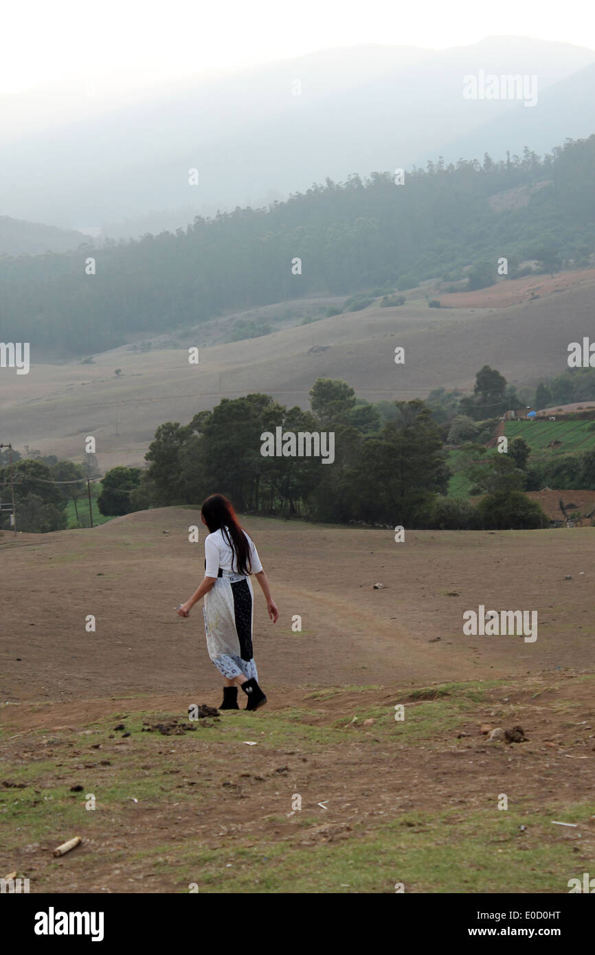 Lonely Girl walking through meadow Banque D'Images