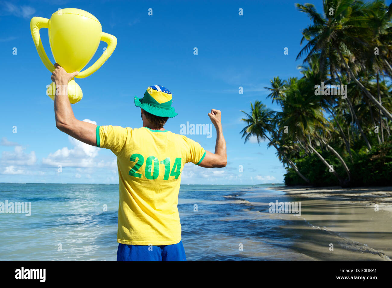 Joueur de football brésilien en 2014 shirt Brésil couleurs holding trophy jusqu'à la plage de Nordeste Bahia Banque D'Images