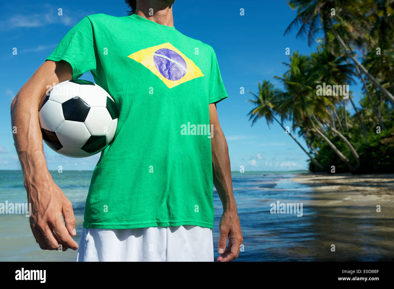 Joueur de football drapeau brésilien en t-shirt holding soccer ball sur la plage, dans le Nordeste Bahia Banque D'Images