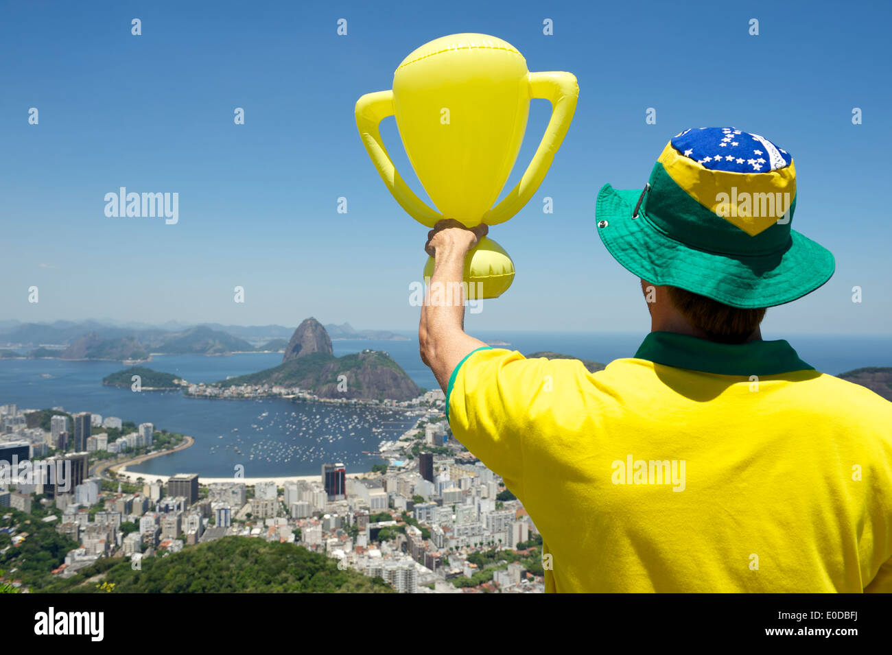 Joueur de football brésilien, debout avec trophy bright sunny Rio de Janeiro skyline avec Pao de Acucar Sugarloaf Mountain Banque D'Images