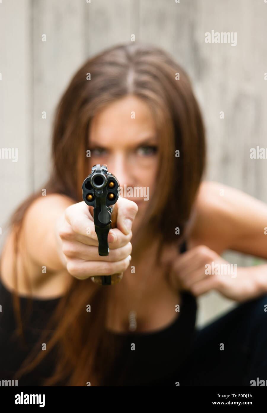Femme s'accroupit et se prépare à faire feu au second coup assaillant Banque D'Images