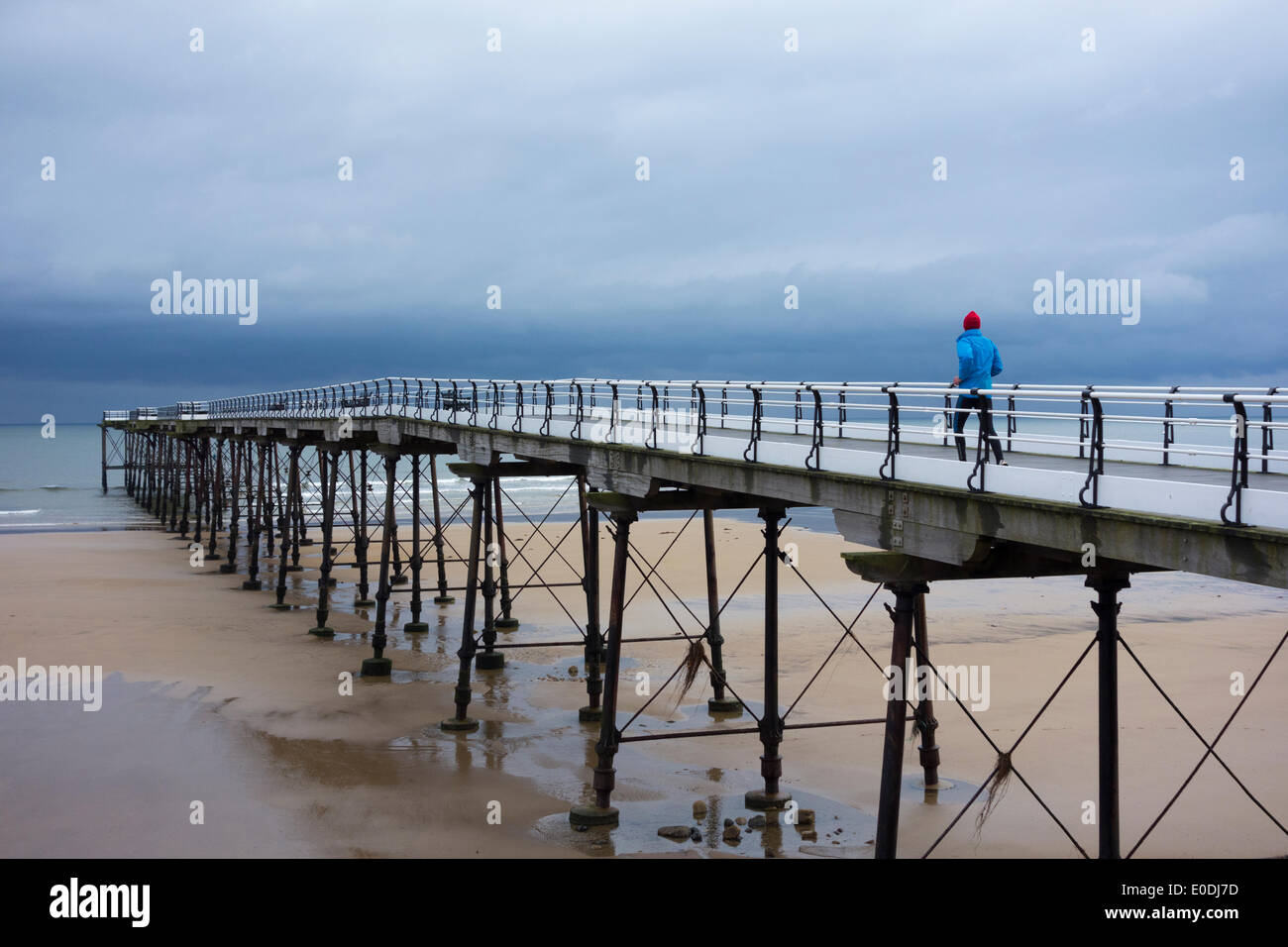 Mature man jogging sur Saltburn pier sous la pluie. Marseille par la mer. Yorkshire du Nord. UK Banque D'Images