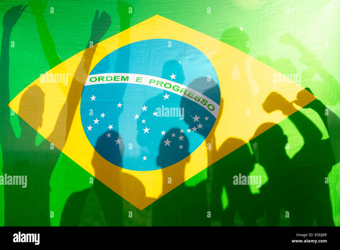 Silhouettes d'ombre de l'équipe de football fête avec ballon de soccer contre drapeau brésilien en plein soleil Banque D'Images