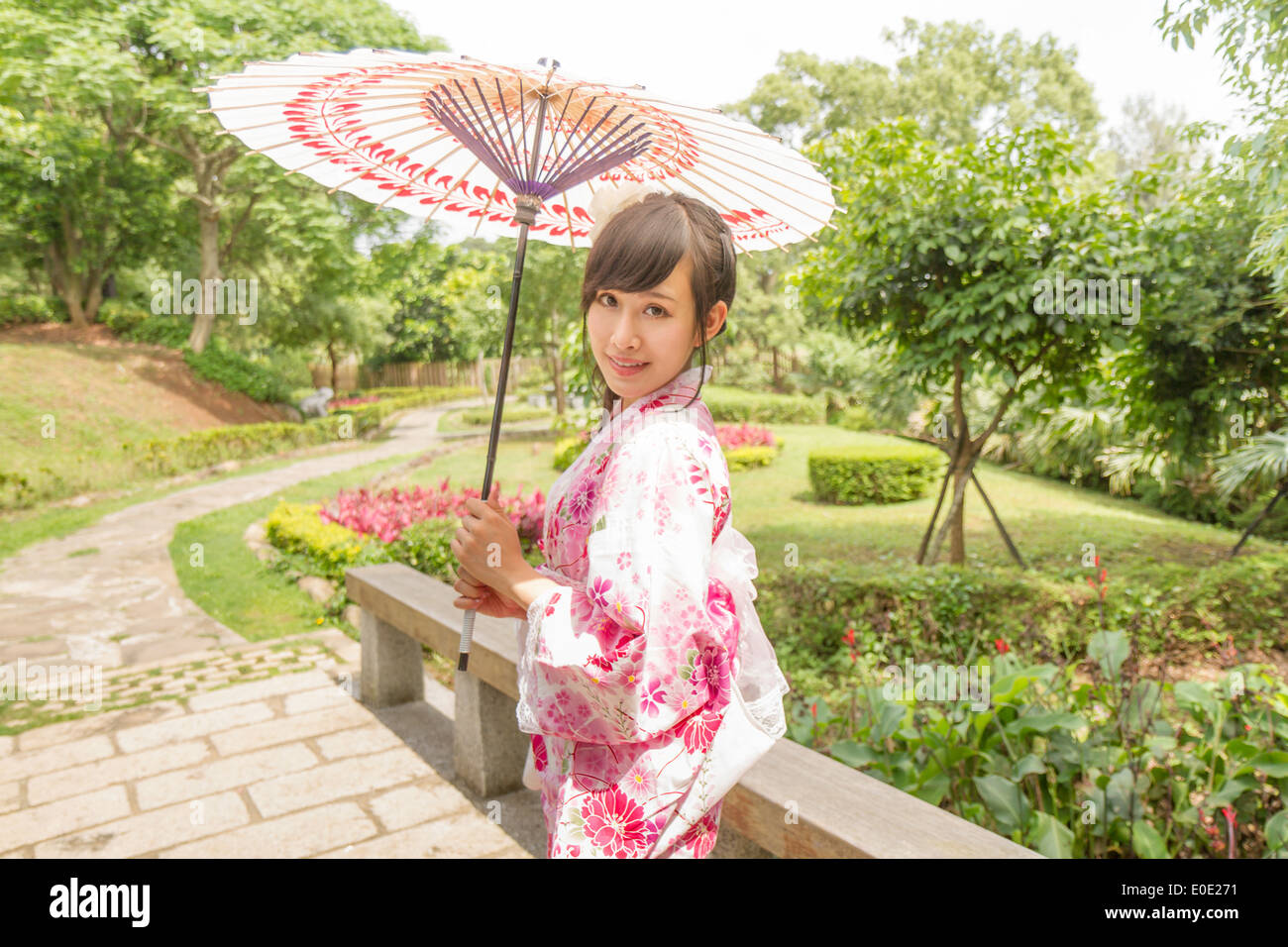 Femme chinoise portant des kimono et holding umbrella dans un jardin de style japonais traditionnel Banque D'Images