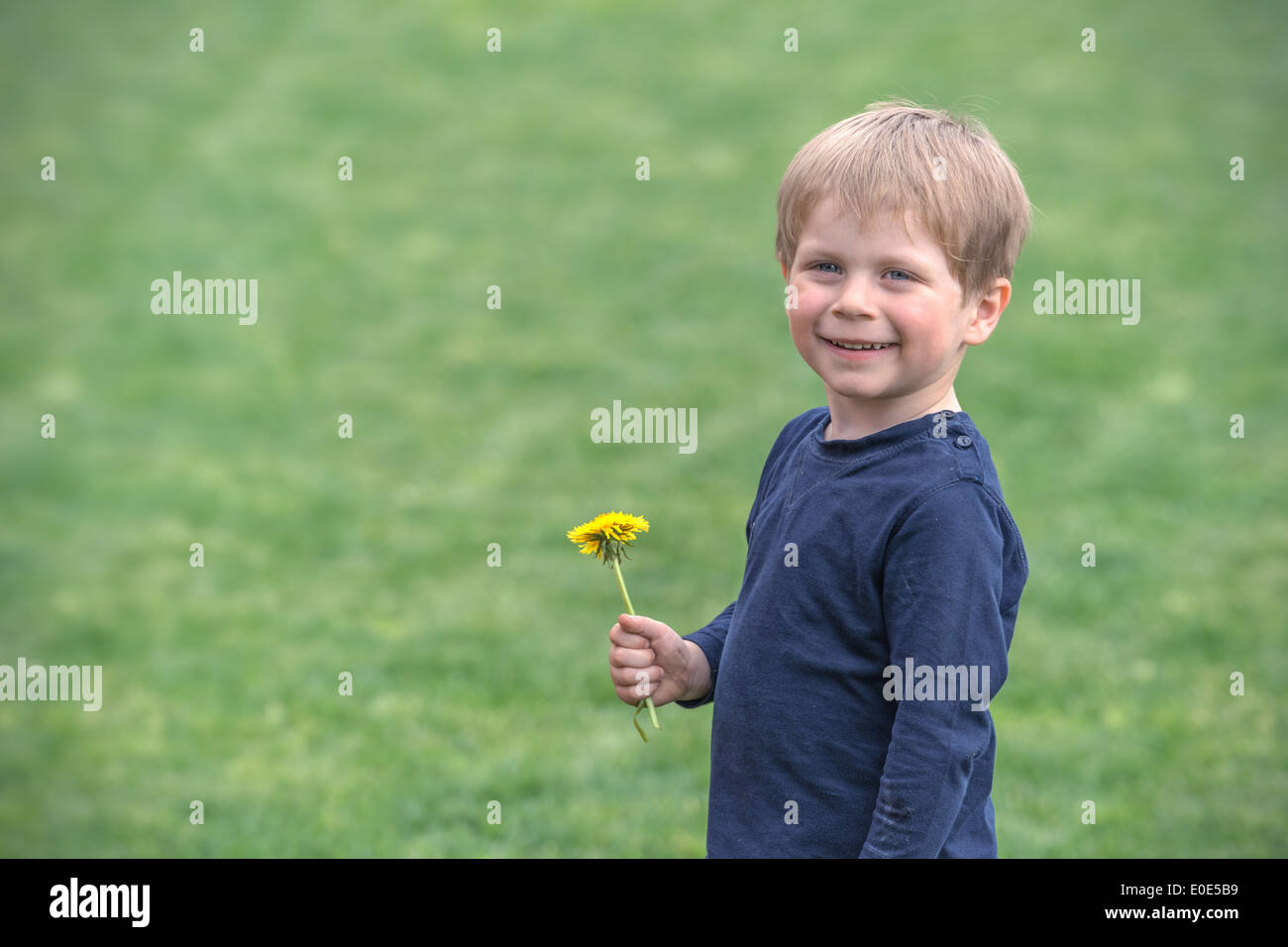 Enfant souriant avec fleur jaune Banque D'Images