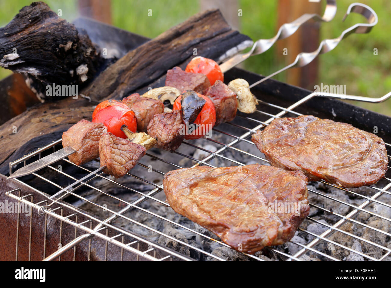 Cuisson sur le barbecue grill steak et brochettes de saucisses assortiment Banque D'Images