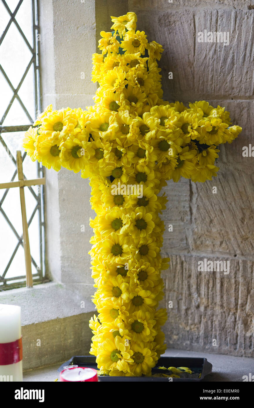 Croix faite de yellow daisy's dans la fenêtre d'une église Banque D'Images