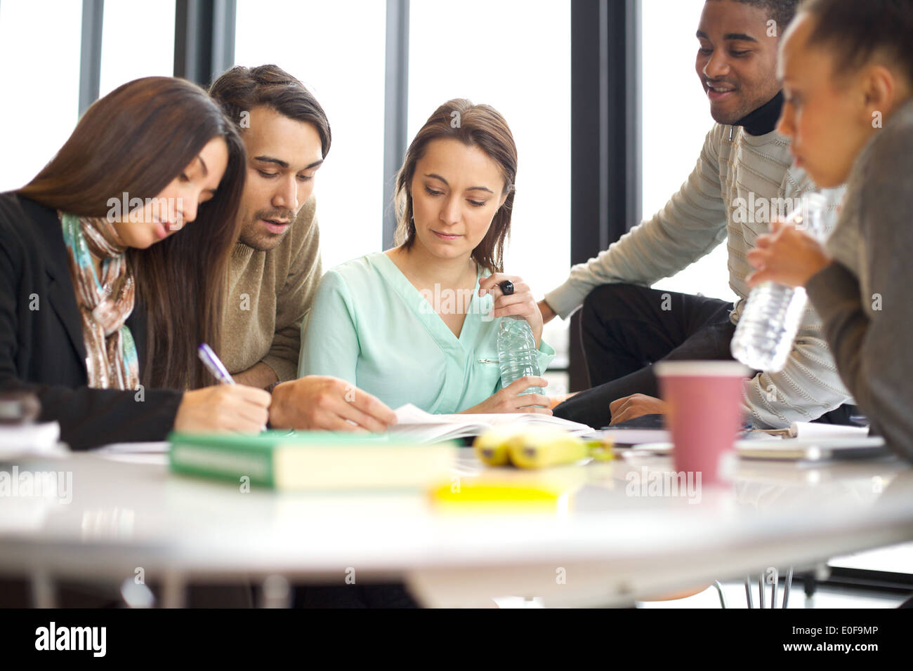 Groupe diversifié d'élèves étudiant dans une bibliothèque. Les jeunes gens assis ensemble à la table fonctionne sur le travail scolaire. Banque D'Images