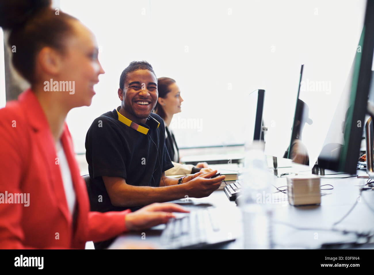 Les jeunes à l'homme à la caméra en souriant tout en travaillant sur l'ordinateur en salle de classe moderne. Les jeunes étudiants qui étudient. Banque D'Images