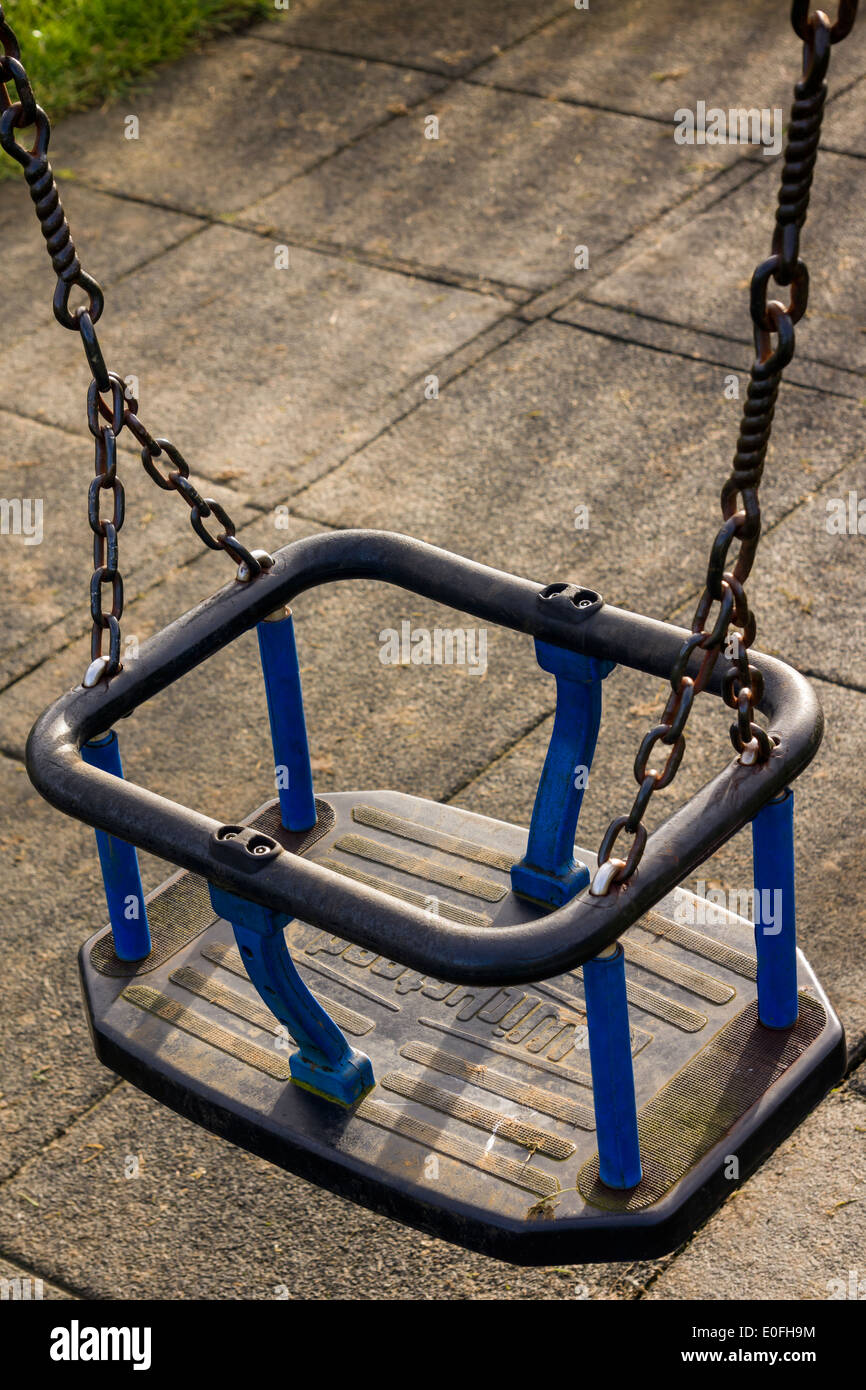 Le siège d'un swing pour enfants dans une aire de jeux publique montre des signes d'utilisation sur de nombreuses années. Banque D'Images