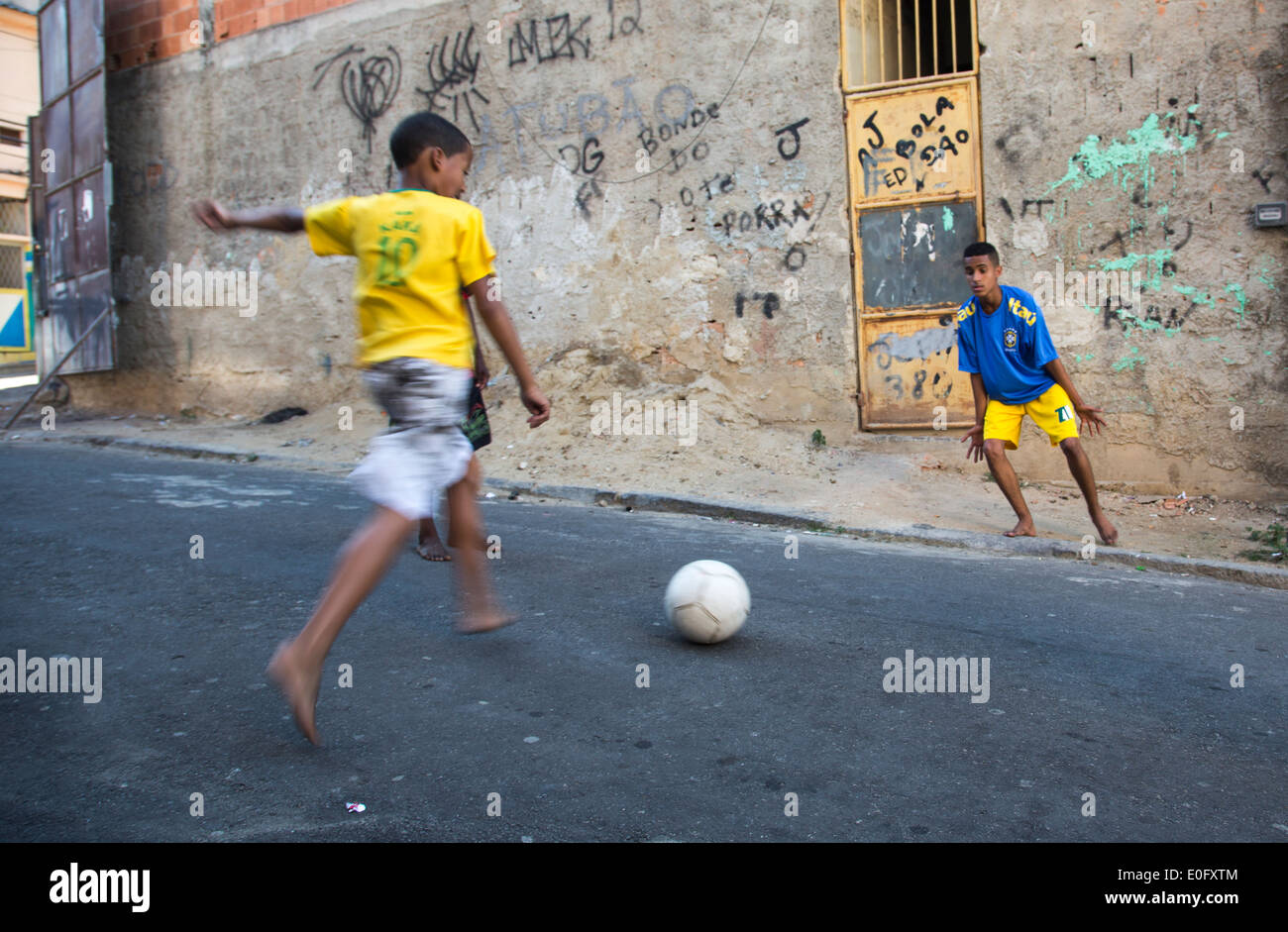 Deux garçons brésilien jouant au football de rue dans une favela de Rio de Janeiro, en maillots de football brésilien Banque D'Images