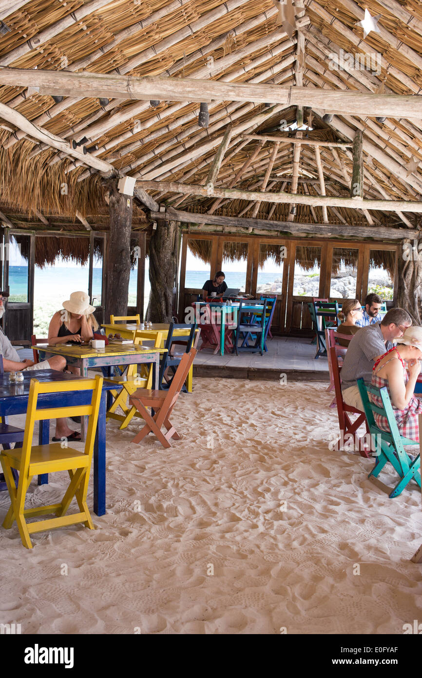 Les touristes dans le restaurant au toit de chaume coloré sur la plage de Tulum avec vue sur l'océan. Banque D'Images