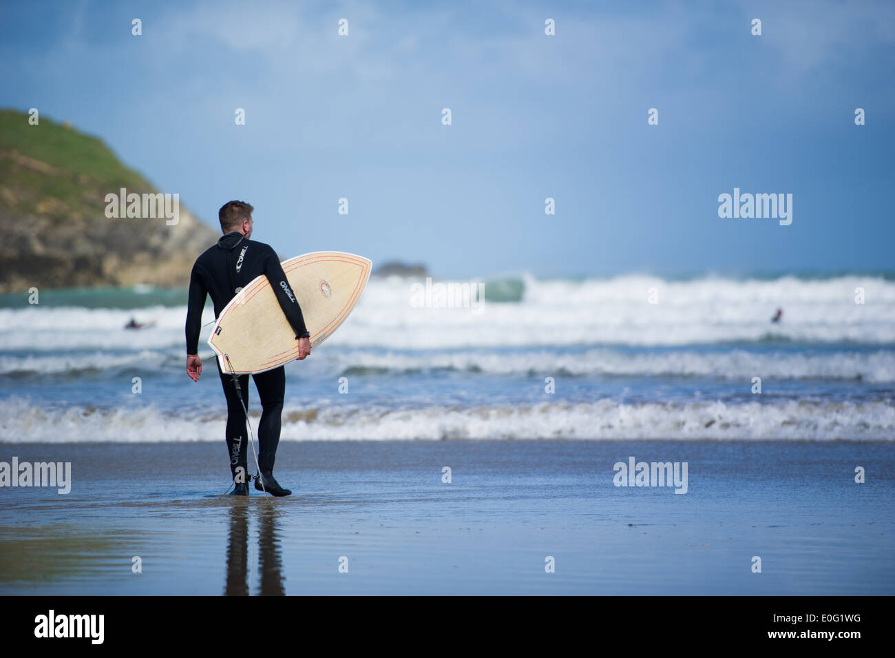 Un surfeur sur la plage à Newquay, Cornwall, Angleterre. Banque D'Images