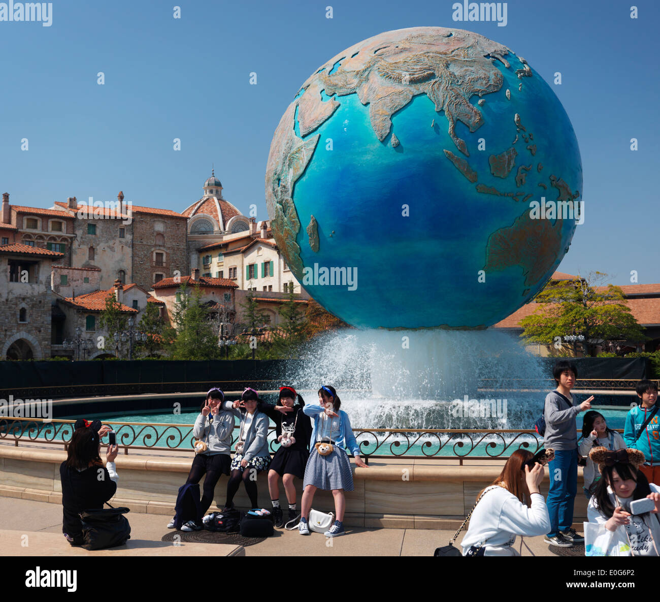 Jeunes filles posant pour une photo à terre fontaine globe à Tokyo Disneysea restort Disney theme park, Japon Banque D'Images